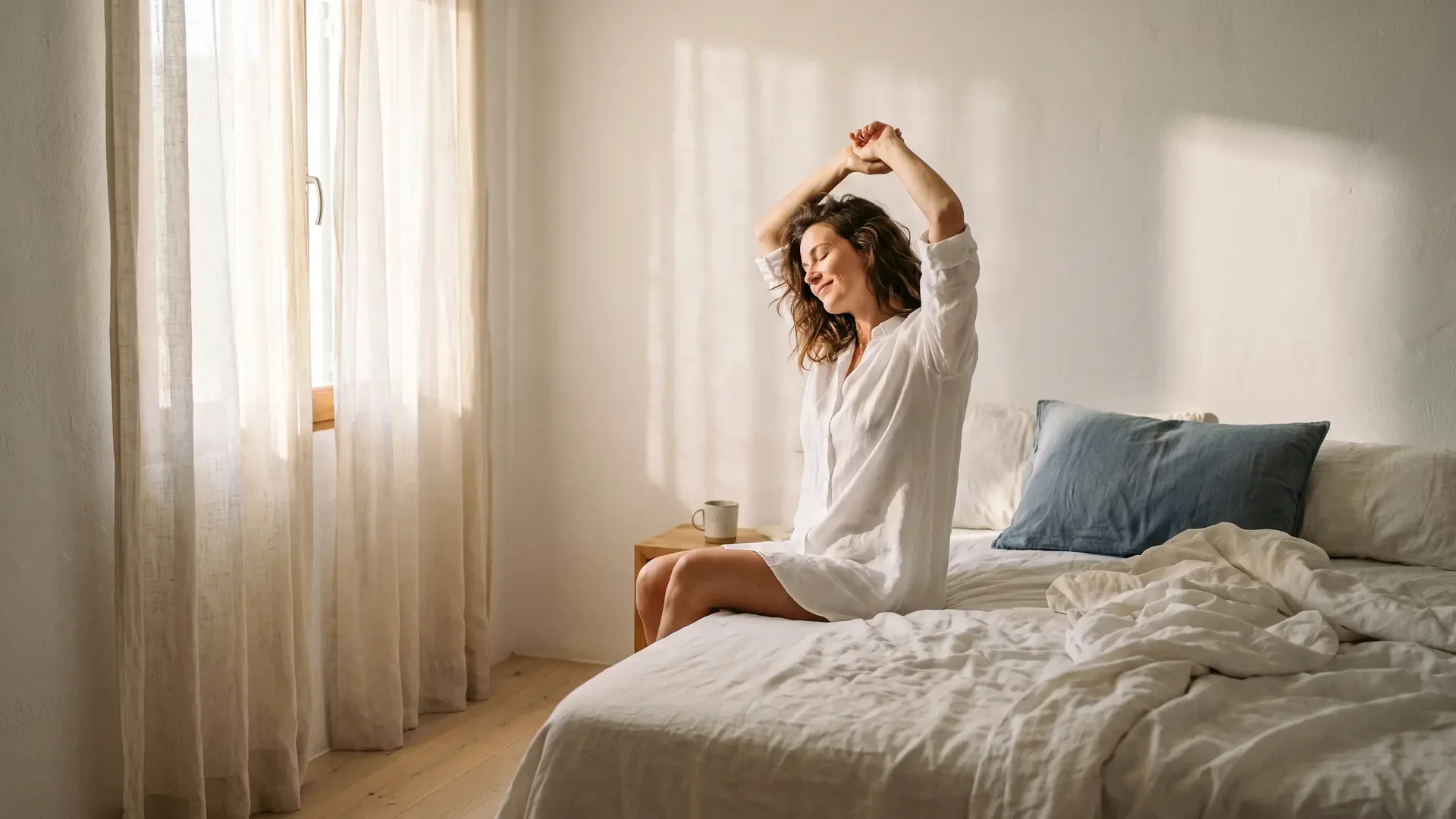 Mujer despertando descansada en un dormitorio luminoso